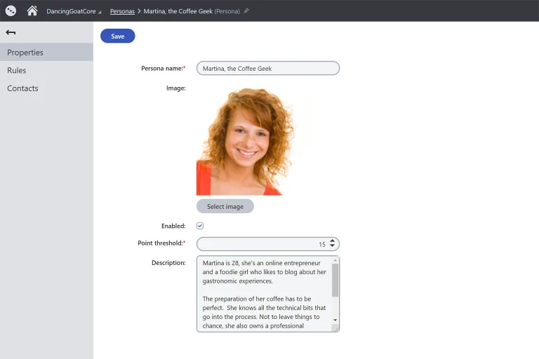 The image depicts a web interface titled "DancingGoatCore" with a subheading "Personas > Martina, the Coffee Geek (Persona)". The page contains a form for editing a persona profile. Form Fields: Persona name: A text field with the value "Martina, the Coffee Geek". Image: A placeholder for an image, currently displaying a smiling woman with curly red hair. There is a button below labeled "Select image". Enabled: A toggle or checkbox option (though the exact control is not visible, it is presumably set to 'on'). Point threshold: A dropdown menu set to "15". Description: A text area containing the following text: "Martina is 28, she's an online entrepreneur and a foodie girl who likes to blog about her gastronomic experiences. The preparation of her coffee has to be perfect. She knows all the technical bits that go into the process. Not to leave things to chance, she also owns a professional". Action Button: A "Save" button at the top of the form. On the left sidebar, there are navigation options listed as "Properties", "Rules", and "Contacts".